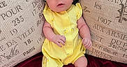Faith joined the competition — help win amazing prizes! baby, infant, yellow_outfit, headband, white_bow, cushions, text_printed, red_blanket, sitting, curious_expression, indoors, soft_fabric, small_hands, legs_crossed, portrait, cute, child, young_baby, comfortable, cozy