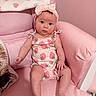 baby, infant, pink, armchair, headband, strawberry_print, blanket, cute, child, sitting, indoors, portrait, clothing, soft_furniture, expression, skin, person, young_child, head, legs