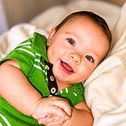 Zander is registered to the contest to win money with this photo: baby, infant, smile, green_shirt, blanket, happy, portrait, closeup, child, cute, face, soft, cozy, hands, young, skin, eyes, clothing, indoors, person