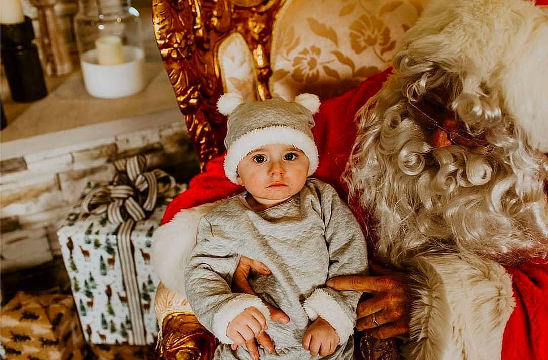 Skyler is registered to the contest to win money with this photo: baby, baby_toddler_clothing, christmas, christmas_decoration, christmas_eve, christmas_ornament, costume_hat, event, fictional_character, fur, fur_clothing, happy, headgear, headwear, holiday, ornament, person, santa_claus, toddler, tradition