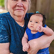 Raziah Morgan is registered to the contest to win money with this photo: elderly_woman, baby, blue_clothing, outdoor, portrait, holding, family, love, affection, person, skin, head, face, nature, tree, casual_wear, smile, tenderness, closeup, human