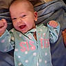 baby, bed, blanket, blue_clothing, child, cozy, eyes, face, fists, happy, indoor, infant, lying_down, open_mouth, photograph, polka_dot, portrait, raised_arms, sleepwear, smiling