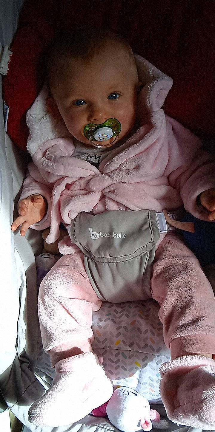 Énora a rejoint le concours — aidez-le/la à gagner de superbes lots ! baby, baby_products, baby_toddler_clothing, cheek, child, drinkware, eye, eyelash, happy, iris, linens, lip, mouth, outerwear, person, pink, sitting, skin, sleeve, toddler