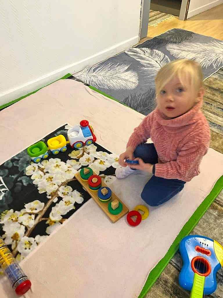 Énora a rejoint le concours — aidez-le/la à gagner de superbes lots ! art, baby, baby_playing_with_toys, baby_toddler_clothing, baby_toys, child, event, floor, flooring, fun, linens, person, play, recreation, room, sitting, toddler, toy, toy_vehicle, visual_arts