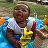 baby, child, smiling, toy, playtime, activity_center, outdoor, grass, car, greenery, happy, infant, colorful, plastic_toy, daylight, casual_clothing, portrait, cute, young_child, laughter