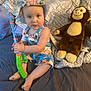 toddler, child, toy, fishing_rod, stuffed_animal, monkey_toy, bed, blanket, clothing, hat, indoor, person, cute, sitting, playful, colorful, soft_toy, happy, young_child, comfort