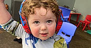 Aiden joined the competition — help win amazing prizes! child, toddler, curly_hair, earmuffs, dinosaur_pajamas, playroom, blue_chair, red_chair, toy, carpet, wall_art, smiling, indoor, person, cute, playful, small_object, young_child, headphones, colorful