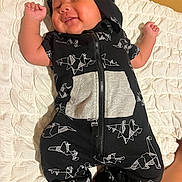 Eric joined the competition — help win amazing prizes! baby, infant, sleeping, peaceful, smiling, portrait, child, onesie, hood, black_clothing, origami_pattern, zipper, quilt, blanket, bed, lying_down, raised_fists, bare_feet, indoor, cozy