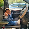toddler, child, car_interior, denim_jacket, denim_jeans, white_shoes, steering_wheel, car_seat, seatbelt, window, sunlight, hand_gesture, playful, smiling, person, vehicle, dashboard, door, cup_holder, floor_mat