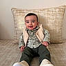 baby, child, smiling, sitting, vest, green_pants, white_shoes, pillow, indoor, happy, face, person, cute, clothing, portrait, home, cozy, infant, plaid_shirt, feet
