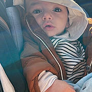 Ibrahim participe au concours pour gagner de l'argent avec cette photo : baby, child, car_seat, jacket, hood, striped_shirt, plush_toy, hand, face, eyes, infant, seatbelt, sunlight, indoor, cute, warm_clothing, portrait, expression, young, cozy