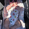 Hazel is registered to the contest to win money with this photo: baby, infant, sunglasses, blanket, onesie, patterned_clothing, hands, feet, face, sunlight, shadow, cute, lying_down, soft_texture, infant_clothing, baby_accessory, pink, relaxing, portrait, child