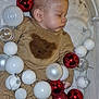 baby, bear_design, blanket, child, christmas_ornaments, clear_balls, cozy, cute, face, head, holiday_decor, indoors, infant, peaceful, red_balls, resting, sleeping, soft_texture, sweater, white_balls