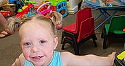 Emily And Allison joined the competition — help win amazing prizes! child, toddler, girl, smiling, portrait, indoor, playroom, toys, toy_kitchen, toy_cars, toy_bus, chairs, table, colorful, blonde_hair, pigtails, blue_shirt, arms_outstretched, carpet, happy