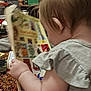 Eden is registered to the contest to win money with this photo: background, blurry, book, carpet, child, clothing, container, cozy, curious, furniture, hair, hand, indoor, motion, person, reading, shelf, skin, toddler, toy