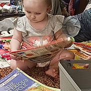Eden joined the competition — help win amazing prizes! basket, book, carpet, child, clothing, colorful, curiosity, floor, foot, furniture, hand, home, indoor, person, pigtails, play, portrait, reading, toddler, toys