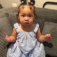 Koda joined the competition — help win amazing prizes! child, toddler, baby, girl, blue_dress, hair_buns, curly_hair, sitting, couch, indoor, furniture, cute, portrait, expression, skin, person, young_child, home, cozy, curious