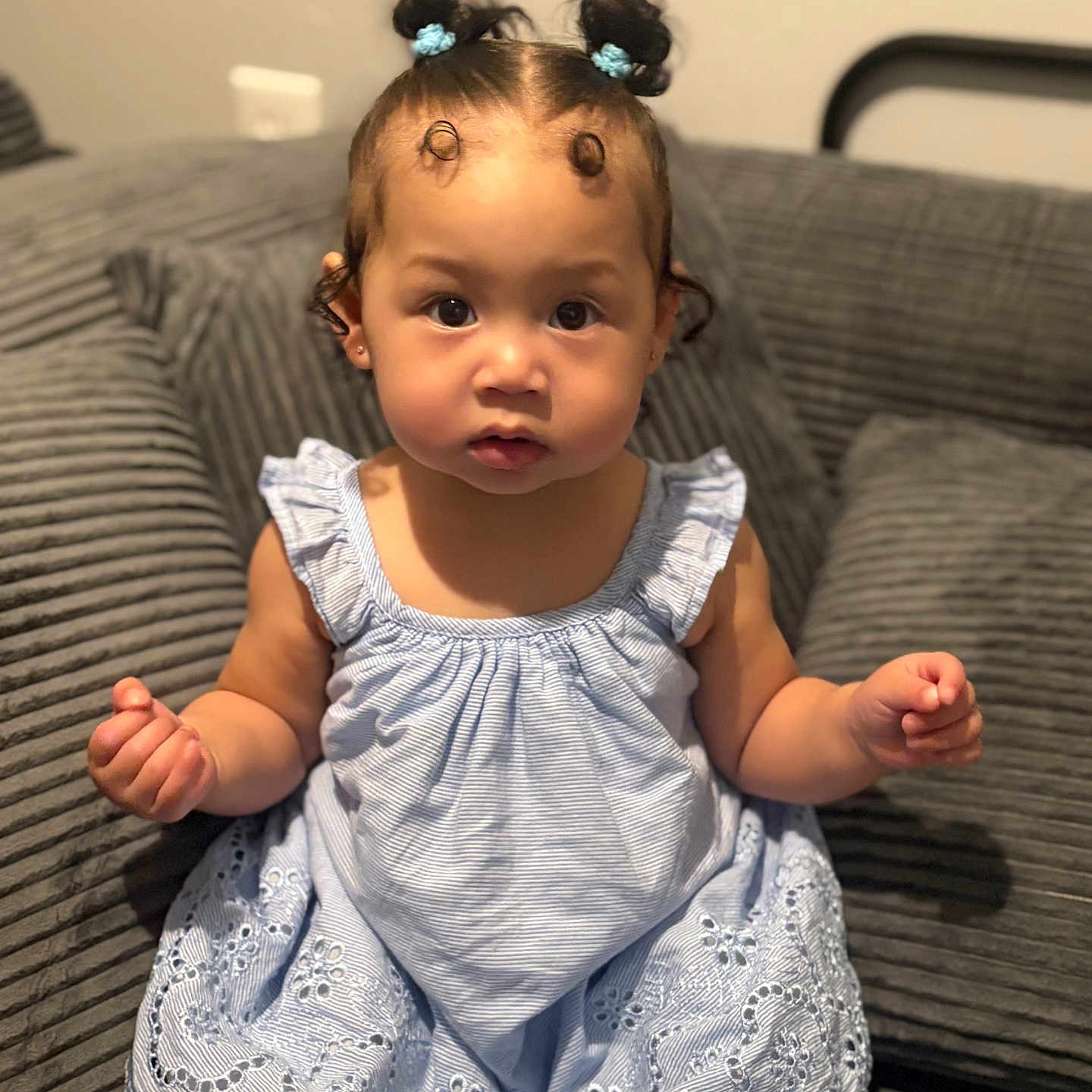 Koda joined the competition — help win amazing prizes! child, toddler, baby, girl, blue_dress, hair_buns, curly_hair, sitting, couch, indoor, furniture, cute, portrait, expression, skin, person, young_child, home, cozy, curious