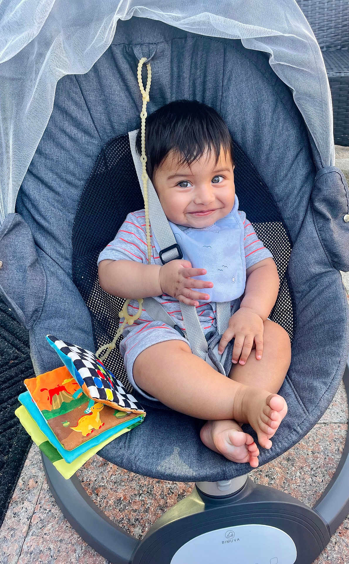 Nikolai is registered to the contest to win money with this photo: baby, child, smiling, baby_rocker, bib, striped_onesie, soft_book, toy, feet, happy, seatbelt, baby_seat, outdoor, daylight, fabric, mesh_back, plastic, playful, cute, infant