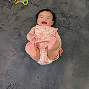 Chloe is registered to the contest to win money with this photo: baby, infant, child, smiling, laughing, romper, toes, feet, legs, face, hair, plush_rug, gray_rug, toy, steering_wheel_toy, juice_box, play_mat, indoor, happy, portrait