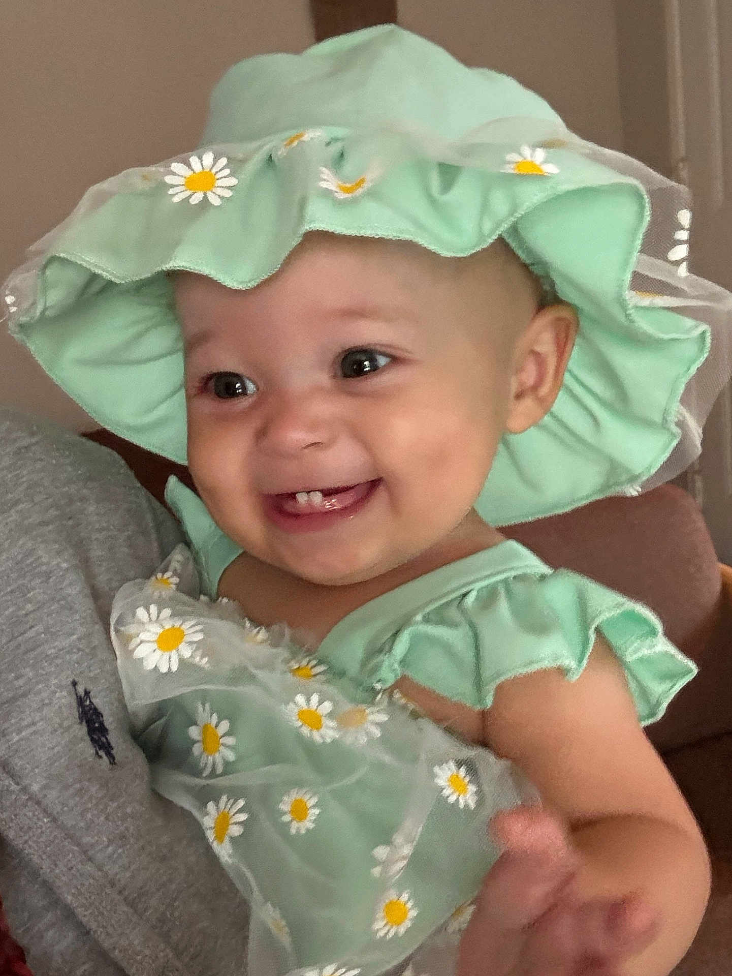 Amiri joined the competition — help win amazing prizes! baby, child, smiling, hat, dress, daisies, green_clothing, person, indoor, happy, cute, face, hand, infant, headwear, apparel, holding, closeup, portrait, human
