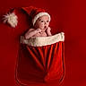 Sohan participe au concours pour gagner de l'argent avec cette photo : baby, santa_hat, christmas_stocking, red_background, holiday, festive, cute, infant, expression, surprised, child, portrait, celebration, warm, cozy, seasonal, christmas, decoration, soft_texture, happy