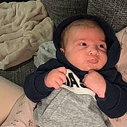 Thiago a rejoint le concours — aidez-le/la à gagner de superbes lots ! baby, infant, hoodie, clothing, person, face, hand, tattoo, couch, blanket, arm, comfort, indoor, portrait, expression, resting, cozy, casual, child, soft