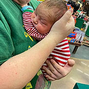 Mason is registered to the contest to win money with this photo: baby, person, holding, striped_clothing, green_shirt, indoor, toys, store, hand, face, head, child, retail, sleeve, human, cute, infant, shopping, background, smile
