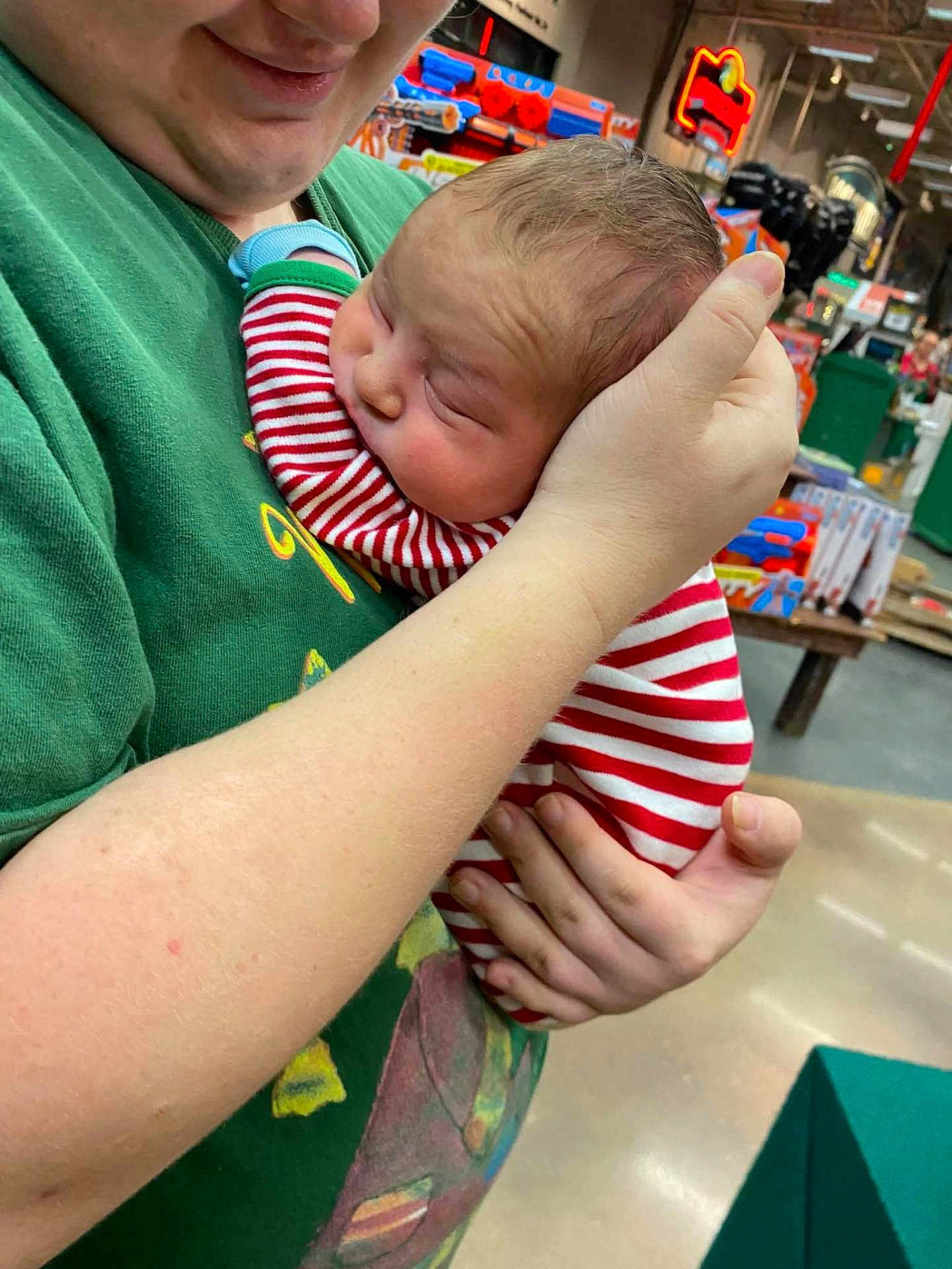 Mason is registered to the contest to win money with this photo: baby, person, holding, striped_clothing, green_shirt, indoor, toys, store, hand, face, head, child, retail, sleeve, human, cute, infant, shopping, background, smile