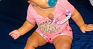 Faith is registered to the contest to win money with this photo: baby, child, pacifier, pink_clothing, hair_buns, bed, indoor, cute, sitting, blue_bedspread, beads, face, person, infant, happy, young, toddler, skin, bright_eyes, cute_hair