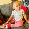 Faith joined the competition — help win amazing prizes! child, toddler, sitting, couch, clothing, pink_pants, floral_shirt, shoe, sock, curly_hair, indoors, cushion, furniture, face, person, expression, casual, home, cozy, yellow_wall