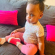 Faith joined the competition — help win amazing prizes! toddler, child, sofa, couch, pillow, pink_pillow, pink_clothing, sitting, indoor, hairstyle, high_puff, floral_shirt, serious_expression, face, hand, footwear, sock, home, furniture, person
