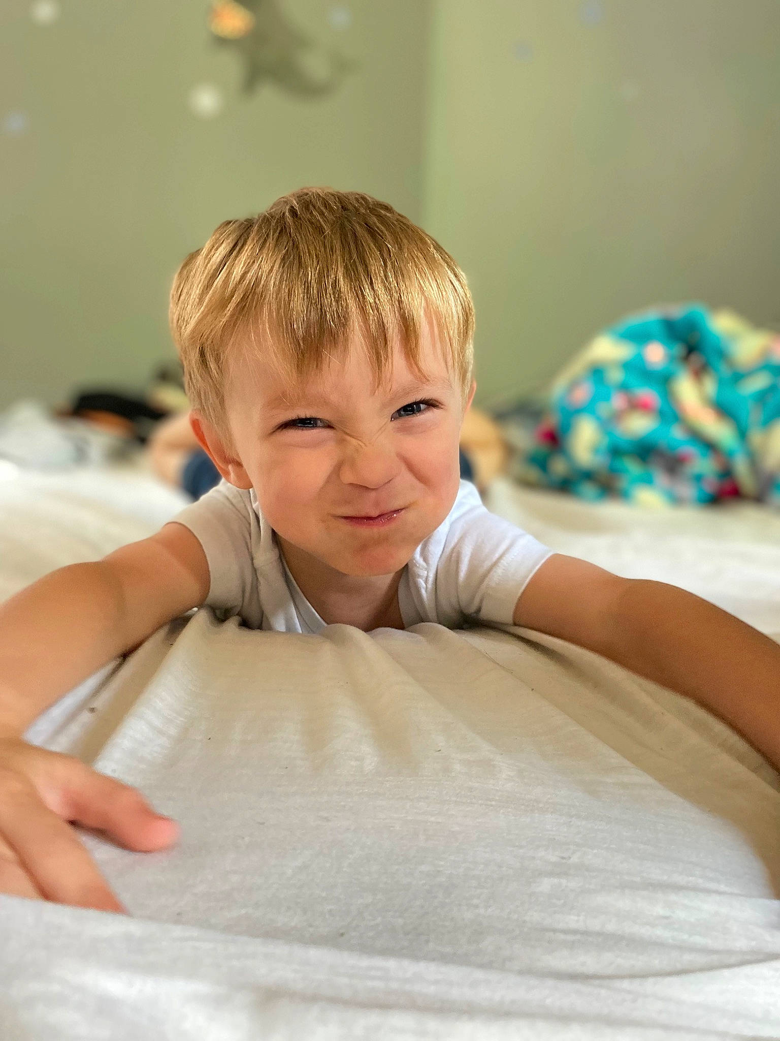 Korben is registered to the contest to win money with this photo: bedding, blond, child, comfort, eye, eyelash, flooring, fun, gesture, happy, leisure, linens, person, portrait_photography, room, shirt, sitting, sleeve, smile, t_shirt