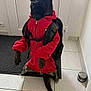 dog, glasses, red_hoodie, backpack, indoor, tile_floor, sitting, pet, animal, black_dog, canine, door, mat, funny_pose, clothing, ears, tail, face, leisure, home