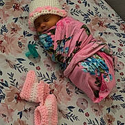 Dayna is registered to the contest to win money with this photo: newborn, baby, sleeping, swaddled, blanket, crocheted_hat, booties, pacifier, floral_pattern, bed_sheet, infant, cute, peaceful, pink, blue_flowers, wrapped, resting, soft, cozy, indoors