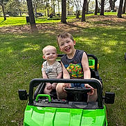 Liam is registered to the contest to win money with this photo: boys, casual_clothing, child, children, daylight, fun, grass, green_car, happy, nature, outdoor, park, play, portrait, smiling, summer, sunny, toy_car, trees, vehicle