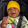 Ace is registered to the contest to win money with this photo: baby, child, yellow_beanie, green_shirt, blanket, hand, smile, face, stroller, seatbelt, infant, happy, cute, clothing, portrait, indoor, person, expression, closeup, cozy
