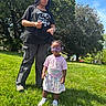 child, children, park, grass, trees, sunny_day, blue_sky, purple_braids, black_tshirt, heart_sunglasses, pastel_skirt, sneakers, outdoor, smiling, standing, nature, daylight, casual_clothing, happy, family