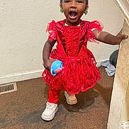 Erza is registered to the contest to win money with this photo: toddler, child, red_dress, beads, hair, smiling, happy, indoor, carpet, sippy_cup, white_shoes, person, standing, banister, handrail, playful, cute, young_child, expression, colorful