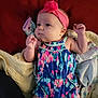baby, infant, headband, flower, romper, colorful_clothing, blanket, fabric, face, skin, hand, fist, lying_down, indoors, cute, child, young, small, portrait, soft
