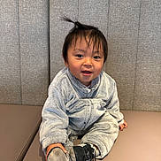 Noah participe au concours pour gagner de l'argent avec cette photo : toddler, child, baby, smiling, sitting, onesie, fuzzy_clothing, shoe, shoe_sole, hair_tuft, bench, cushion, gray_background, indoor, cute, happy, person, face, cozy, playful