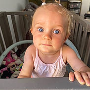 Kamélia participe au concours pour gagner de l'argent avec cette photo : baby, blue_eyes, child, close_up, crib, curious, cute, expression, face, furniture, hand, home, indoor, person, pigtails, pink_clothing, portrait, room, toddler, toy