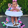 baby, child, high_chair, smiling, outdoor, garden, hedge, dolls, toys, plush_toys, pink_clothing, headband, bow, sitting, portrait, happy, infant, playtime, pavement, babyjoy