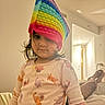 Aarya joined the competition — help win amazing prizes! child, pajamas, pop_it_toy, rainbow, hat, indoor, person, bedroom, furniture, relaxed, animal_print, cute, toy, childhood, home, child_wearing_hat, casual, young_child, playful, colorful