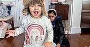 Aarya joined the competition — help win amazing prizes! toddler, child, indoor, hat, sweater, rainbow, floor_rug, expression, smile, serious, lamp, table, shoes, headband, black_jacket, wood_floor, door, bag, person, home_interior