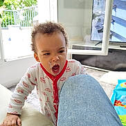 Ami participe au concours pour gagner de l'argent avec cette photo : toddler, child, yogurt, messy, pajamas, indoor, living_room, sofa, couch, hand, curly_hair, expression, clothing, face, person, carpet, television, window, jeans, home