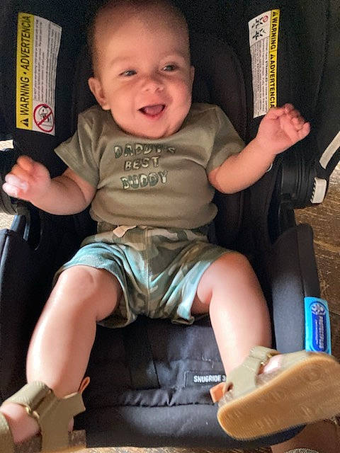 Jaime is registered to the contest to win money with this photo: baby, baby_carriage, baby_toddler_clothing, car_seat, chair, cheek, child, comfort, facial_expression, finger, fun, happy, human_leg, lap, leg, person, sitting, smile, thigh, thumb