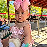 Athalia is registered to the contest to win money with this photo: baby, bench, child, clothing, curious, face, hand, hat, headband, holding, outdoor, pavilion, people, person, pink_bow, shadows, sunlight, toy, trees, wristband