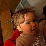 Emy a rejoint le concours — aidez-le/la à gagner de superbes lots ! brown_shirt, bunny_design, casual_clothing, child, cozy, curious, curly_hair, cute, expression, face, indoor, person, portrait, red_blanket, smiling, toddler, warm_lighting, wide_eyes, wooden_wall, young_child
