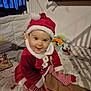 Emy participe au concours pour gagner de l'argent avec cette photo : baby, bed, blanket, child, christmas, cute, festive, happy, holiday, indoor, infant, person, playtime, portrait, red_hat, santa_claus_costume, smiling, striped_leggings, toys, warm_clothing